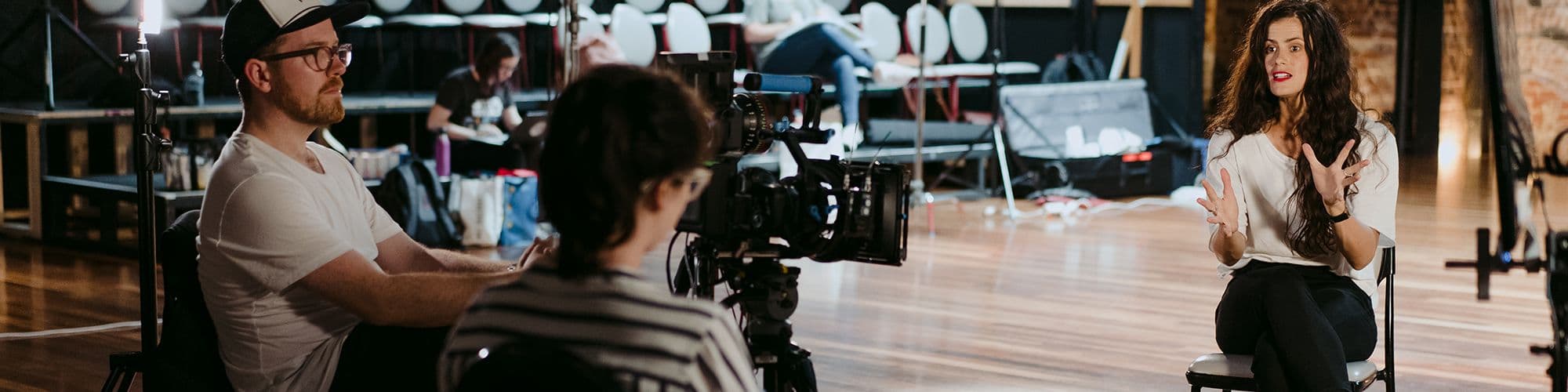 A woman being interviewed by a film crew in a theatre.