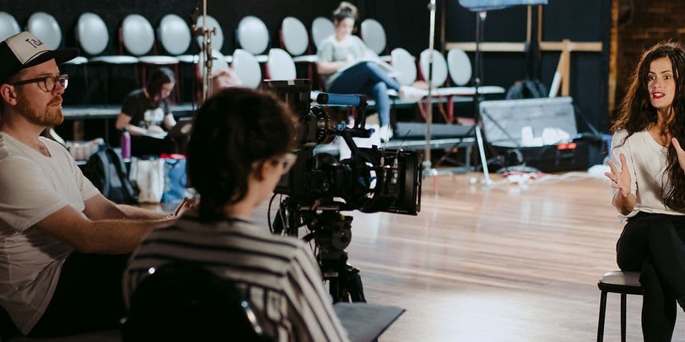 A woman being interviewed by a film crew in a theatre.